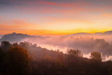 Obraz premium Picturesque orange sunrise over the river with morning mists. View of the Benedictine Abbey in Tyniec. Autumn landscapes of Poland.