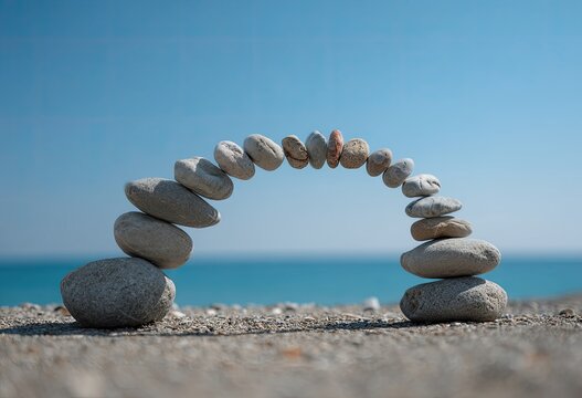 A graceful stone arch, delicately balanced on a sandy beach against a serene blue ocean under a clear sky