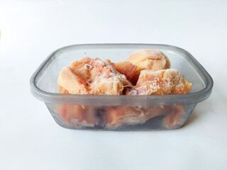 Side View of Frozen Raw Chicken Pieces Stored in Transparent Plastic Food Container for Kitchen Meal Preparation