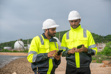 Environmental engineer or workers examining waste water along a large industrial waste water or pollution monitoring and maintenance to ensure systems operate effective environmental regulations.