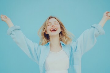 a young women with joy and laughter and her eyes closed and mouth wide open in a delighted grin. Both arms are raised high in a celebratory gesture, light blue background 