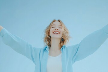 a young women with joy and laughter and her eyes closed and mouth wide open in a delighted grin. Both arms are raised high in a celebratory gesture, light blue background 