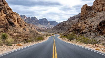 Winding road through rocky canyon landscape with mountains in background