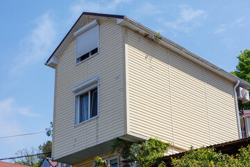 A large yellow house with a slanted roof and a window