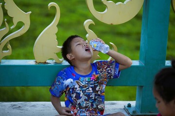 The boy drank water from the bottle with great thirst.
