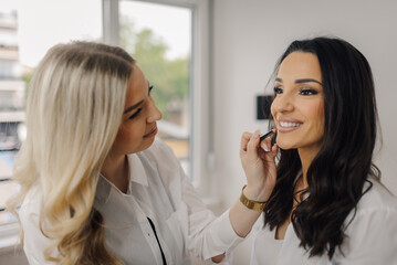 Professional makeup artist applying lipstick on client's lips