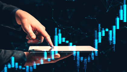 Businessperson analyzing financial market data on tablet with glowing stock chart graphics on dark digital background in futuristic business concept.