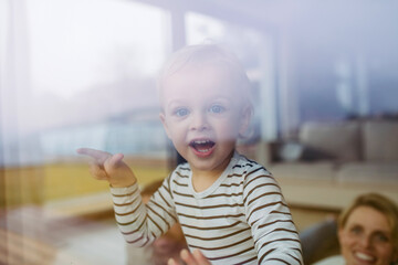 Cute boy looking out of window, laughing.