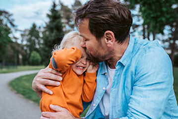 Father comforting young son during emotional moment in park