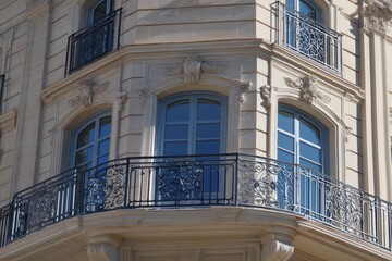 Elegant wrought iron balcony and windows reflecting the blue sky, enhancing the luxury facade.