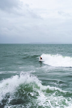 Surfer riding a wave on a cloudy day