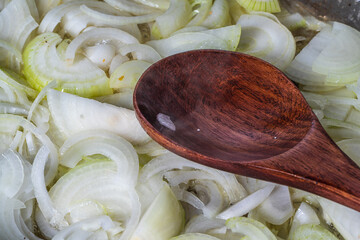 The onion is fried in a pan and a wooden spatula stirs it. The process of cooking onion soup and...