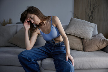 Obraz premium Upset woman feeling not perfect enough touching her head sitting on the sofa