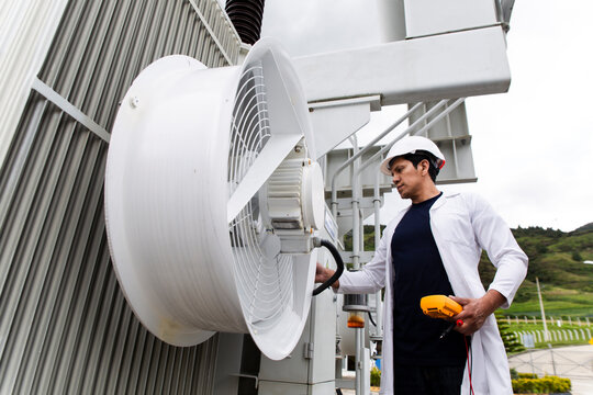Engineer inspecting transformer with voltmeter at wind farm