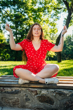 Redhead woman meditating while sitting on bench