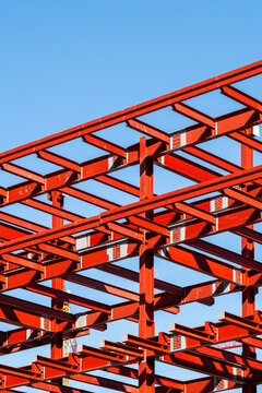 Close-up of red steel beams on construction site, contemporary architecture, geometric framework, progress in urban development, modern building design.