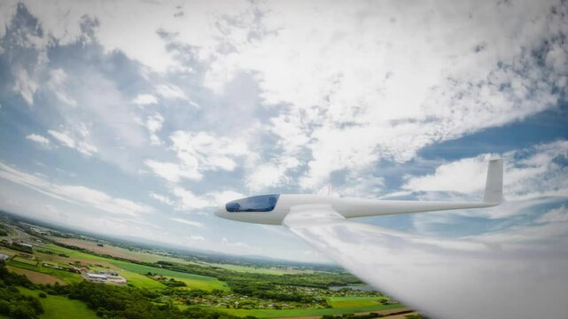 A sleek, white glider soars gracefully over a picturesque landscape beneath a vibrant sky.