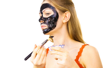 Woman applying black mask to skin face