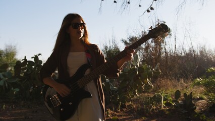 Girl With Sunglasses Plays Bass Musical Instrument In The Countryside Among Tree