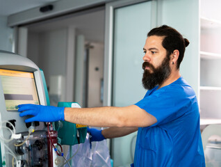 Doctor operating plasmapheresis machine in hospital room