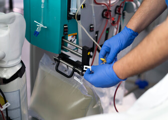 Doctor using dialysis machine filtering blood of patient in hospital