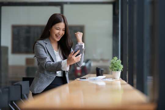 Asian businesswoman using laptop, smartphone, talking about work at bar, coffee shop