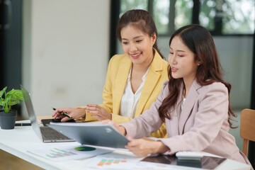 Group of two Asian businesswomen using laptops and tablets having a meeting about working together.