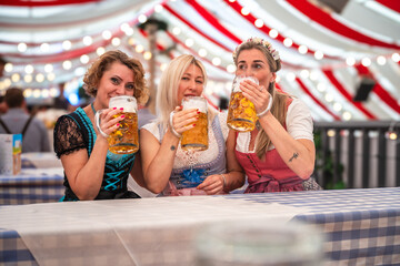 Women in traditional dress toast with beer during a joyful celebration. Oktoberfest Munich, Gäubodenvolksfest Straubing, Maidult Regensburg, Germany