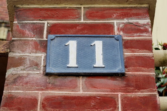 Num&eacute;ro 11. Plaque de num&eacute;ro de rue sur fa&ccedil;ade de brique rouge.