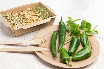 Green pepper and mint branches in a cardboard disposable dish. Sprouted grains of wheat, peas and mung bean in cardboard container