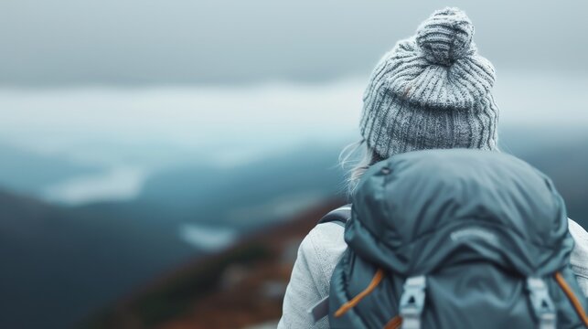 This captivating image features a hiker standing atop a misty mountain peak, evoking feelings of adventure, exploration, and the breathtaking beauty of nature in every direction.