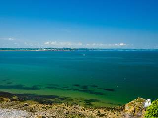 Rocky beach with distant views of Tenby town (Caldey Island, Tenby, Wales, United Kingdom)