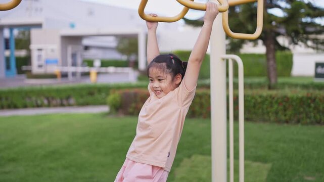 Joyful young girl swinging on monkey bars in a playground, enjoying outdoor play and fostering childhood happiness in a sunny park atmosphere