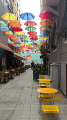 Istanbul, Turkey - June 10, 2022: Colorful umbrellas hanging over a vibrant street with yellow...