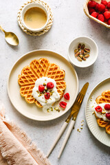 Süsses Frühstück mit Waffeln, Joghurt und frischen Himbeeren auf zwei Tellern. Eine Tasse Kaffee, Draufsicht.
