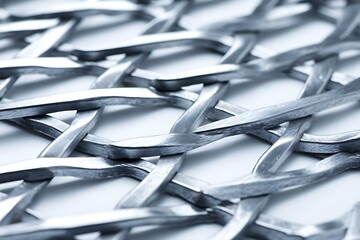a close-up shot of a metal mesh with visible textures, dents, and imperfections, illuminated with soft, diffused light, isolated in a