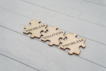 Three wooden jigsaw puzzle pieces with text PROBLEM and SOLUTION. Problem solving concept.