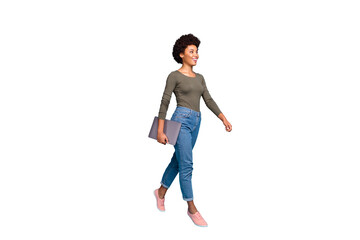 Full length photo of positive cheerful afro american girl hold her netbook go university for education learning wear casual style outfit denim jeans pink sneakers isolated blue color background