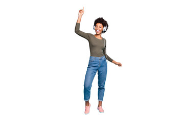 Full length photo of cheerful funky mulatto girl raise her hand listen music sing stereo song use headset dance wear lifestyle green pullover denim jeans sneakers isolated blue color background