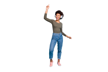 Full length photo of cheerful funky mulatto girl raise her hand listen music sing stereo song use headset dance wear lifestyle green pullover denim jeans sneakers isolated blue color background