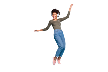 Full body photo of cheerful funny mulatto girl have free time listen music on her headset dance sing enjoy wear stylish green pullover denim jeans sneakers isolated over blue color background
