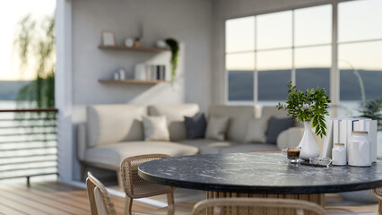 Coffee cup and flower vase on black marble round table in a room with sofas and river view outside.