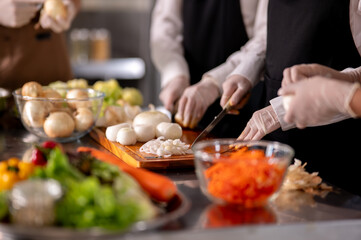 Close up of gloved hands chef holding knife chopping onions on cutting board at kitchen counter.