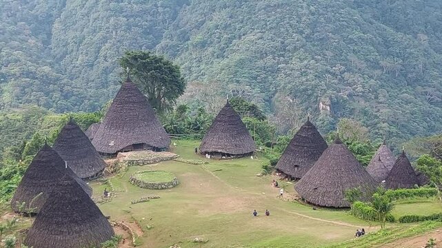 Traditional Mbaru Niang houses of Wae Rebo, Indonesia, nestled amidst lush green mountains. A unique cultural village landscape with Cone-shaped thatched roofs