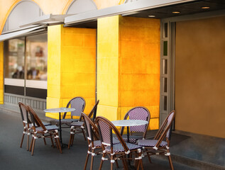 Yellow wall, chairs and tables in an open-air cafe