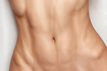 un primer plano de un abdomen liso y tonificado, con una apariencia plana. La piel se ve bien cuidada, con una textura natural y algunas peque&ntilde;as imperfecciones
