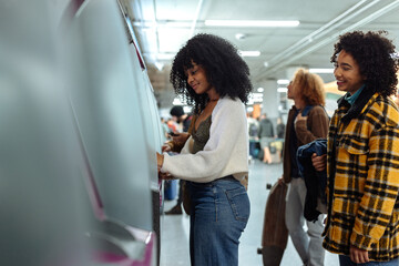 Young women purchasing train tickets at ticket machine