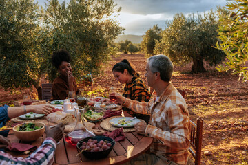 Farmers enjoying dinner together at olive grove after harvesting olives