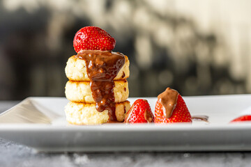 Cottage cheese pancakes or cheesecakes with strawberries and chocolate on a white plate. The concept of a delicious and healthy breakfast. Restaurant serving of the dish. Close-up.