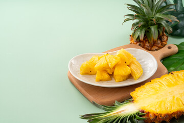 Fresh pineapple chunks served in a pineapple bowl on green table background.